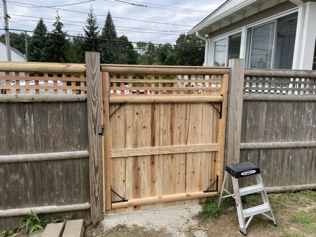 A newly installed wooden gate in a backyard fence.